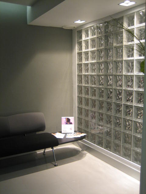 Zona de espera con tabique de pavés, iluminación empotrada y mobiliario contemporáneo diseñada por Ane Valverde Interiorismo en Donostia - San Sebastián