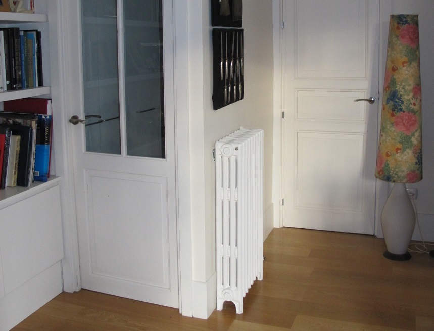 Zona de paso renovada con puertas blancas, suelo de madera clara y elementos funcionales tras una reforma con ecodiseño realizada por Ane Valverde Interiorismo en Donostia - San Sebastián